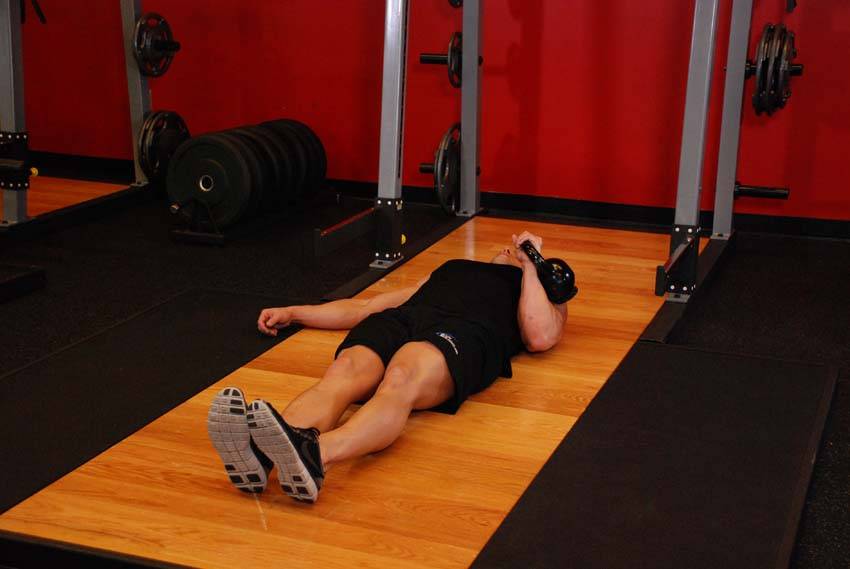 Press en el suelo a un brazo con kettlebell, inicio